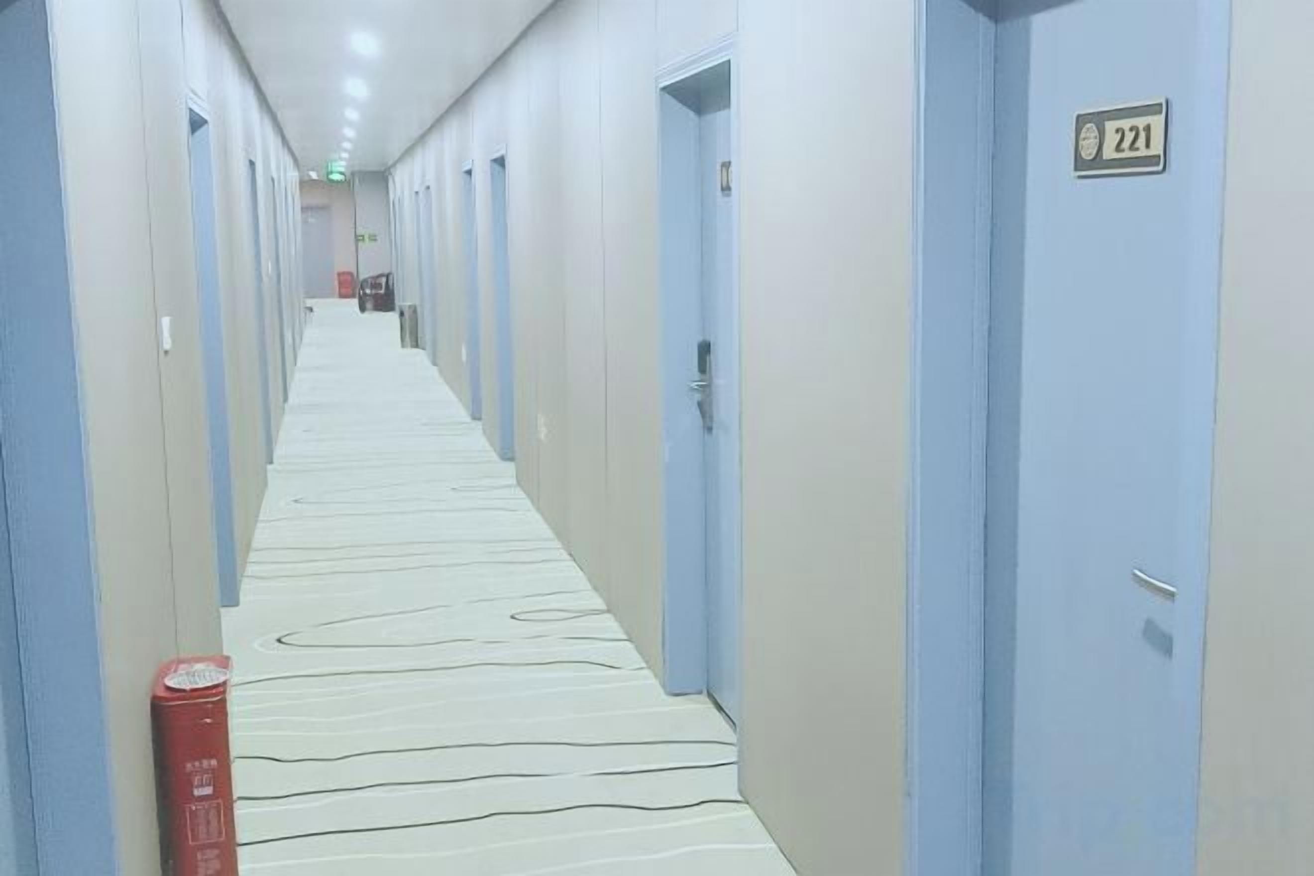 A hotel corridor with doors numbered 221, a fire extinguisher, and a patterned carpet.