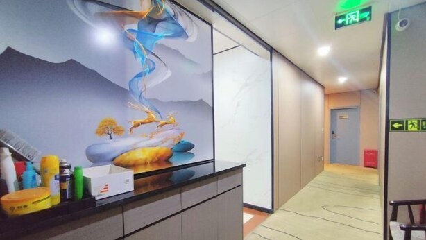 Un espace d’accueil d’hôtel au design moderne, comprenant un comptoir où sont disposés divers articles de toilette et une grande fresque abstraite sur le mur.