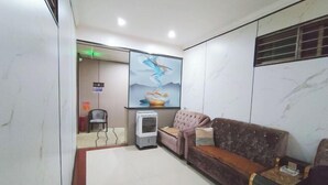 Un espace d’accueil avec un mur en marbre, un canapé, un climatiseur et un tableau.