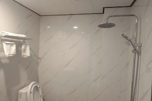 Une salle de bain moderne équipée d’une douche, de toilettes et d’un porte-serviettes.
