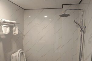 Um banheiro moderno com chuveiro, vaso sanitário e porta-toalhas.
