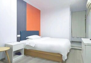 Una cama individual con estructura de madera, una mesita de noche blanca y una pequeña mesa.