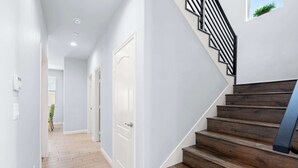 Un couloir moderne avec un escalier en bois et une porte blanche.