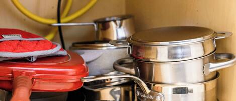 A kitchen with stainless steel cookware, including pots and pans, and a red appliance.