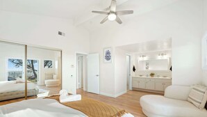 Une chambre d’hôtel moderne, dotée d’un grand lit, d’un canapé, d’un ventilateur de plafond et offrant une vue sur l’extérieur.