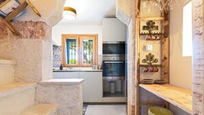 Una cocina estrecha con escalones de piedra, una ventana de madera y un horno empotrado.