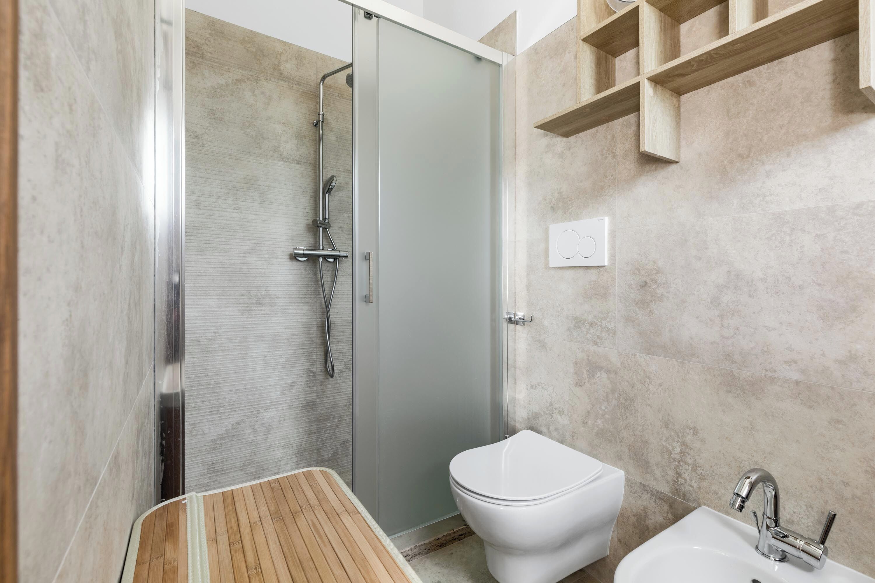 A modern bathroom with a shower, toilet, and sink.