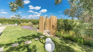 Un jardín con cerca de madera, piedras para caminar y un objeto esférico blanco.