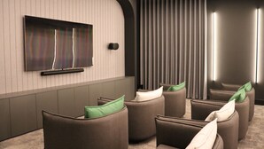 Una sala de cine moderna con asientos curvos, un televisor de pantalla plana grande e iluminación ambiental.