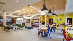 Un moderno comedor con disposición de asientos temática de tren, techo de madera y paredes de color amarillo brillante.