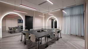 Una sala de conferencias moderna con una larga mesa, sillas e iluminación colgante.