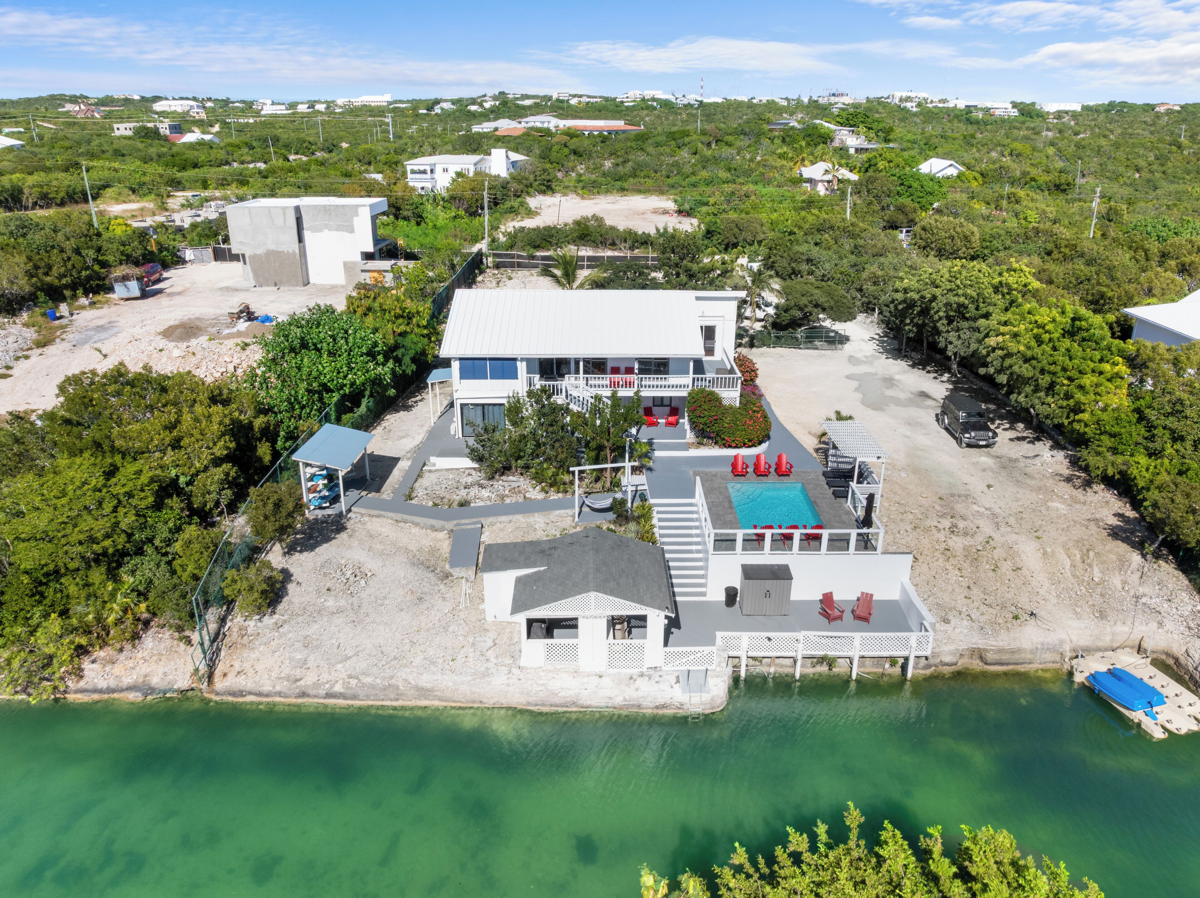 An aerial view of a coastal property with a swimming pool, multiple buildings, and a beach area.