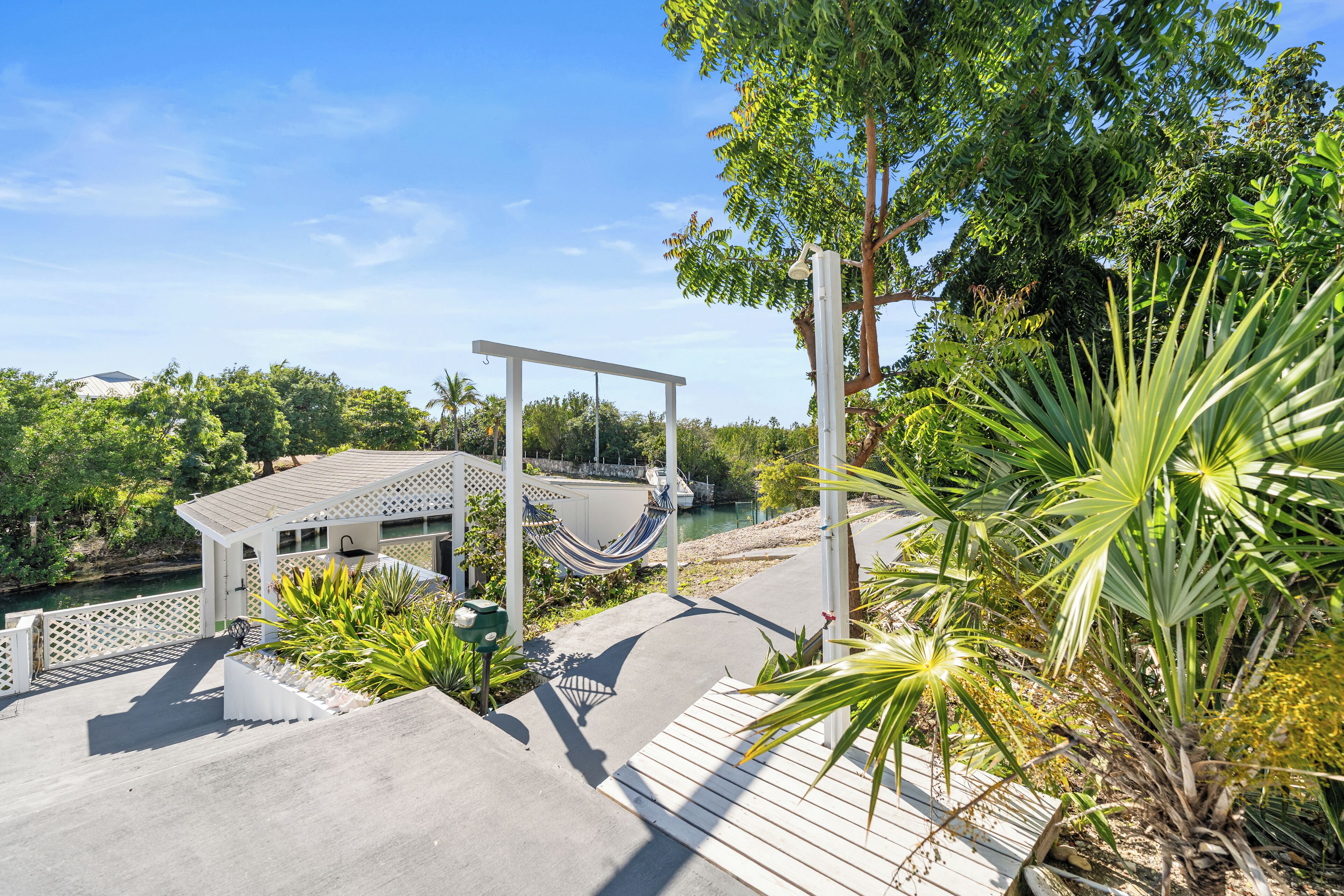 Un espace extérieur moderne agrémenté d’un hamac, d’une terrasse en bois et d’une végétation luxuriante.