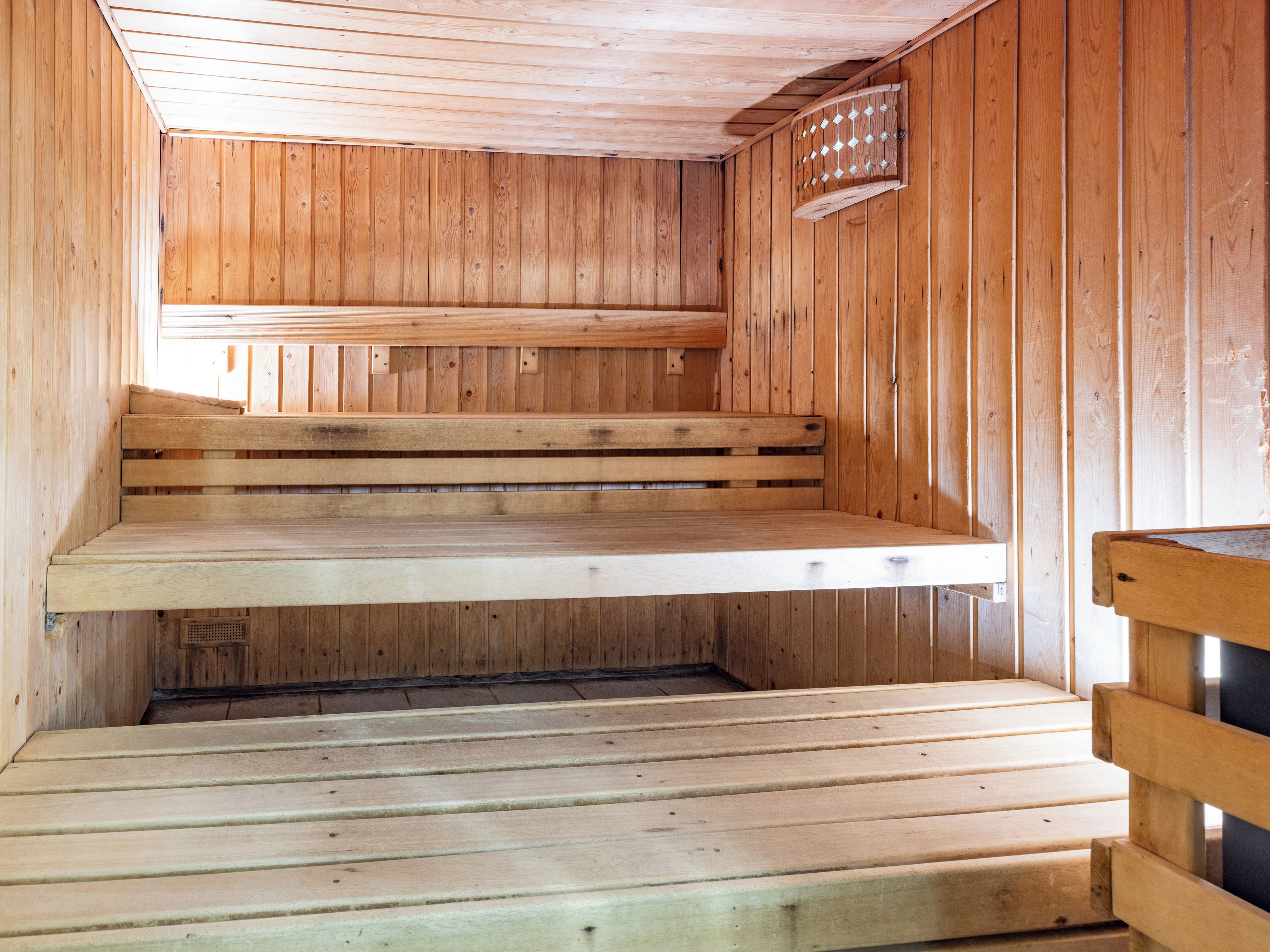 Un sauna en bois, doté de bancs et d’un plancher incliné.
