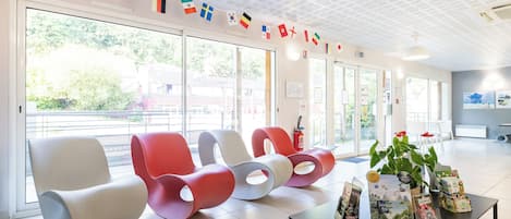 A modern waiting area with colorful flags, comfortable seating, and informational brochures on a table.