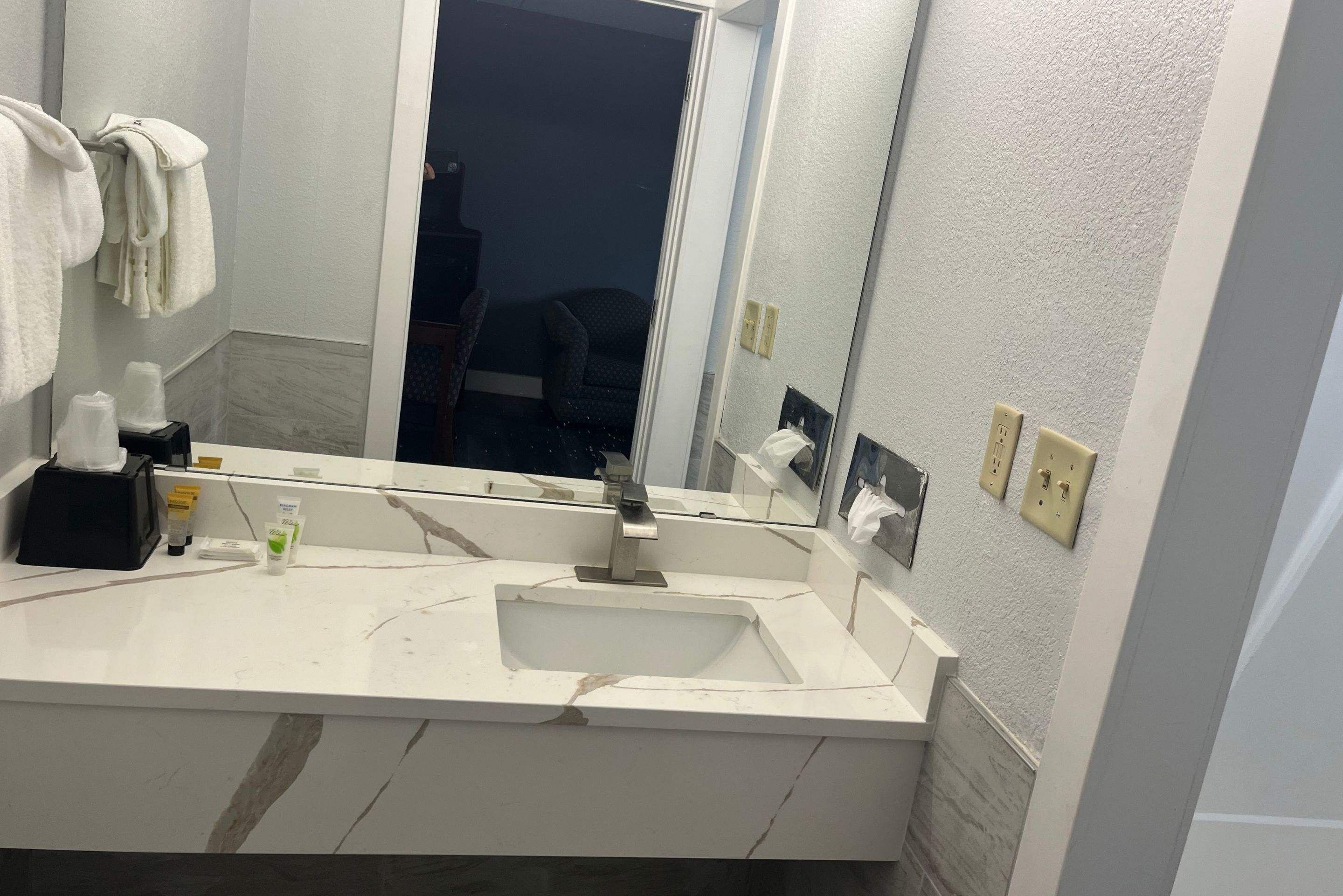 A bathroom with a white sink, a mirror, and a towel rack.