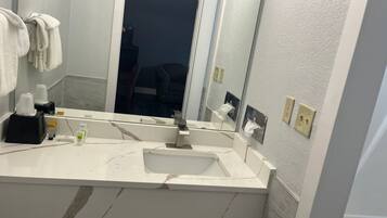 A bathroom with a white sink, a mirror, and a towel rack.