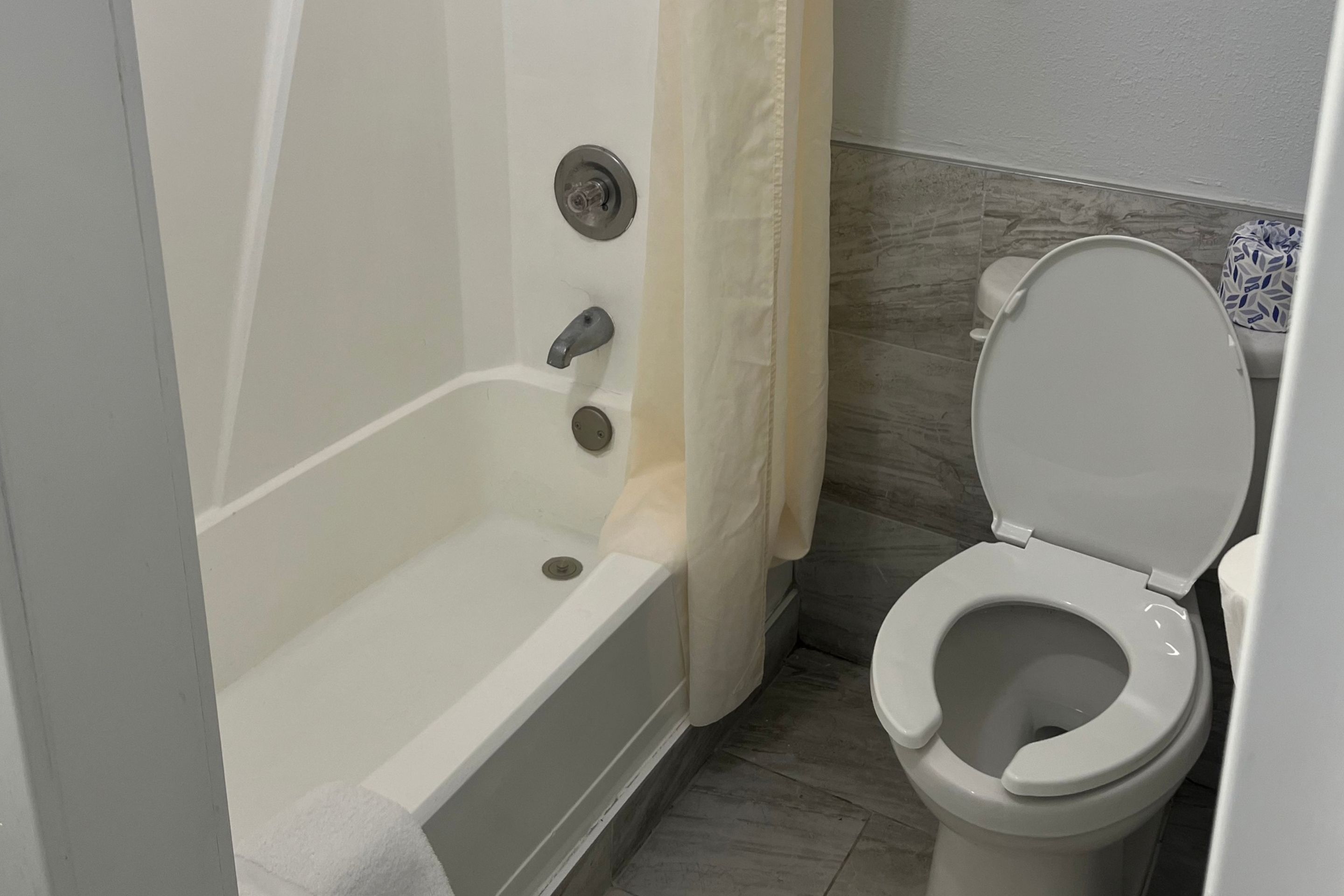 A bathroom with a bathtub, toilet, and shower curtain.