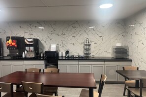 A modern kitchen with a marble backsplash, a coffee machine, and a water dispenser. - Coratel Inn and Suites By Jasper Roseville (Roseville)