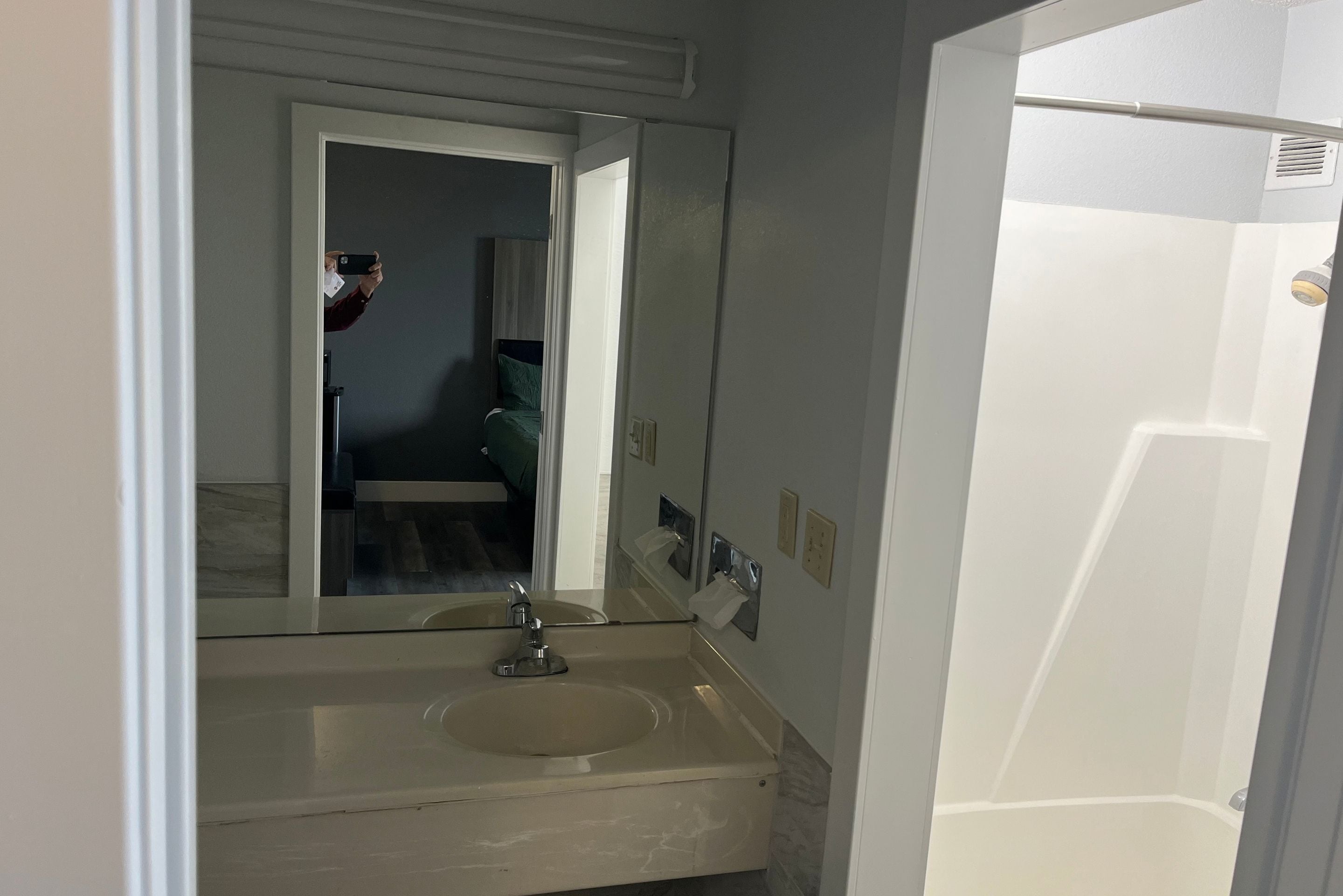 A bathroom with a sink, mirror, and a door leading to another room.