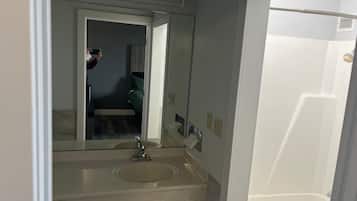 A bathroom with a sink, mirror, and a door leading to another room.