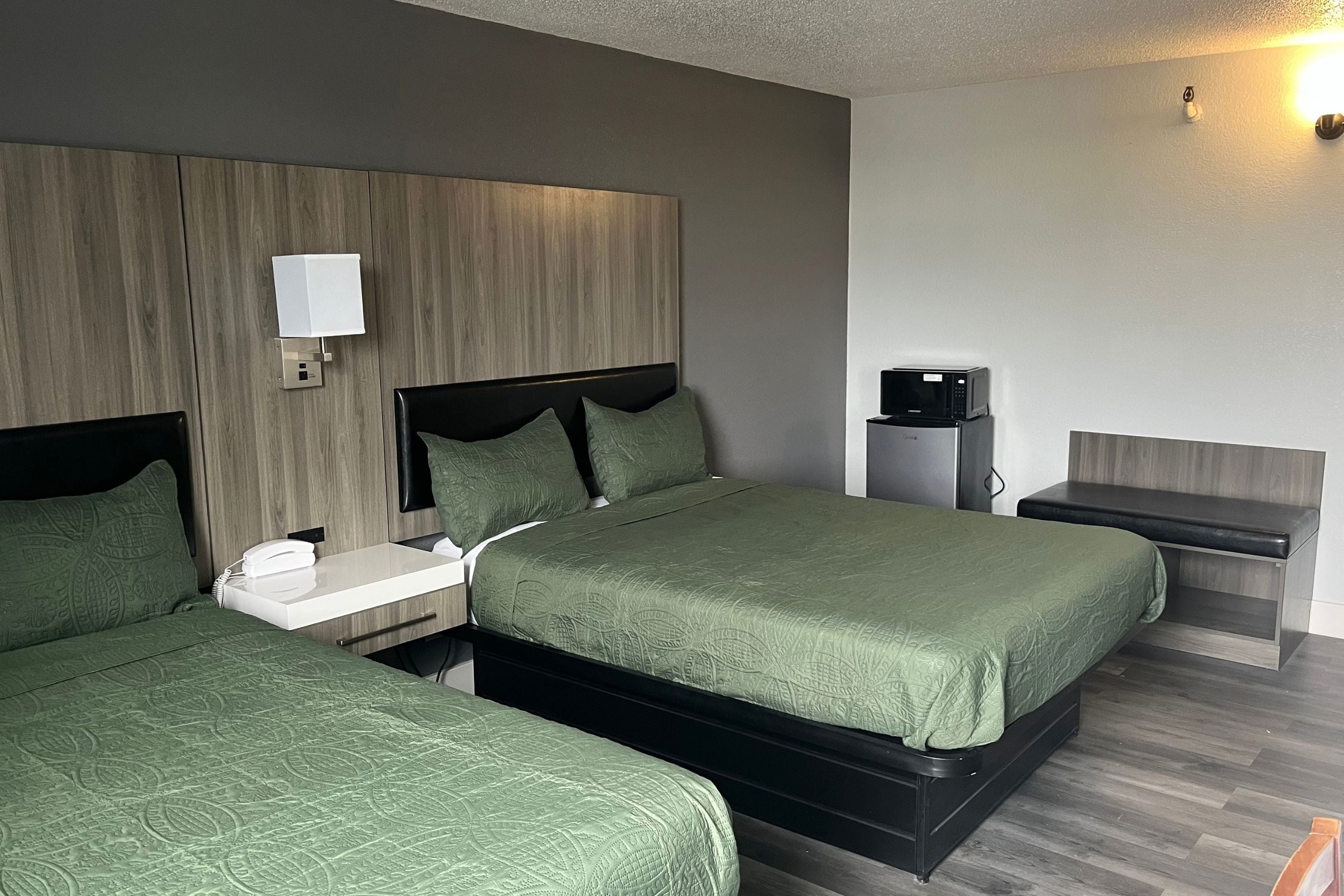 Habitación de hotel con dos camas, una mesita de noche, una lámpara, un teléfono y un microondas.