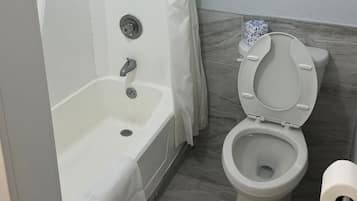 A bathroom with a bathtub, toilet, and a shower curtain.