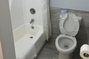 Un baño con bañera, inodoro y cortina de ducha.