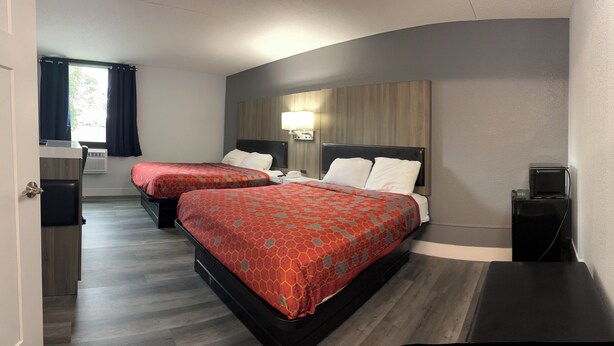 A hotel room with two beds, a desk, a chair, and a lamp. - Coratel Inn and Suites By Jasper Roseville (Roseville)