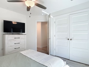 A bedroom with a bed, a television on a dresser, a ceiling fan, and a white door. - 2 BR Canal-Front Paradise, Heated Pool, Beaches & Gulf Coast (Rotonda West)