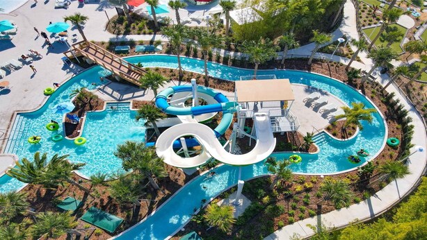 Un parque acuático con varias toboganes y piscinas, rodeado de palmeras y sillones de descanso.