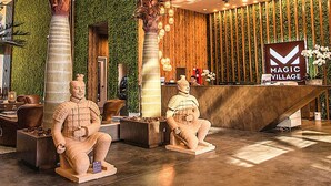A reception area with a wooden reception desk, a sign reading "MAGIC VILLAGE," and two stone statues. - Sophisticated Family Villa Spacious 4br, Prime Disney Area Location! (Kissimmee)