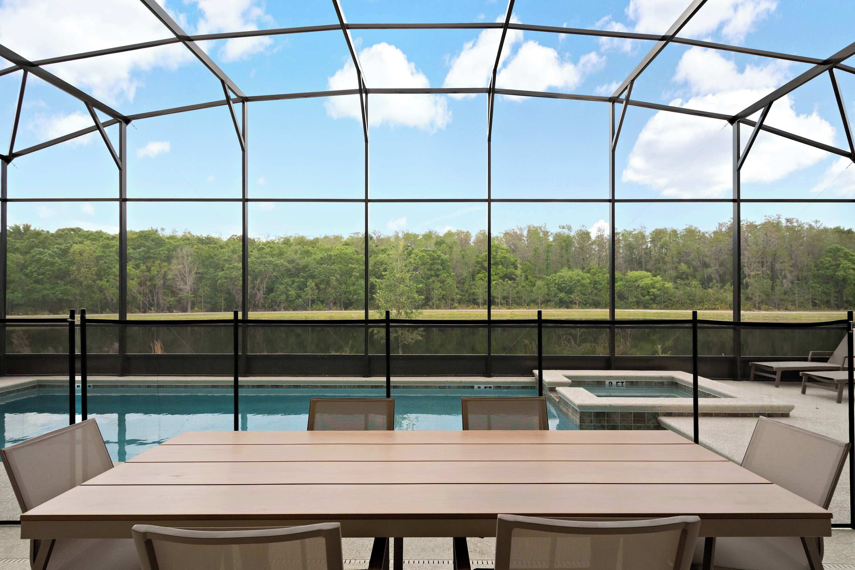 Ein überdachter Außenbereich mit Pool, Sitzgelegenheiten und Blick auf einen Wald.