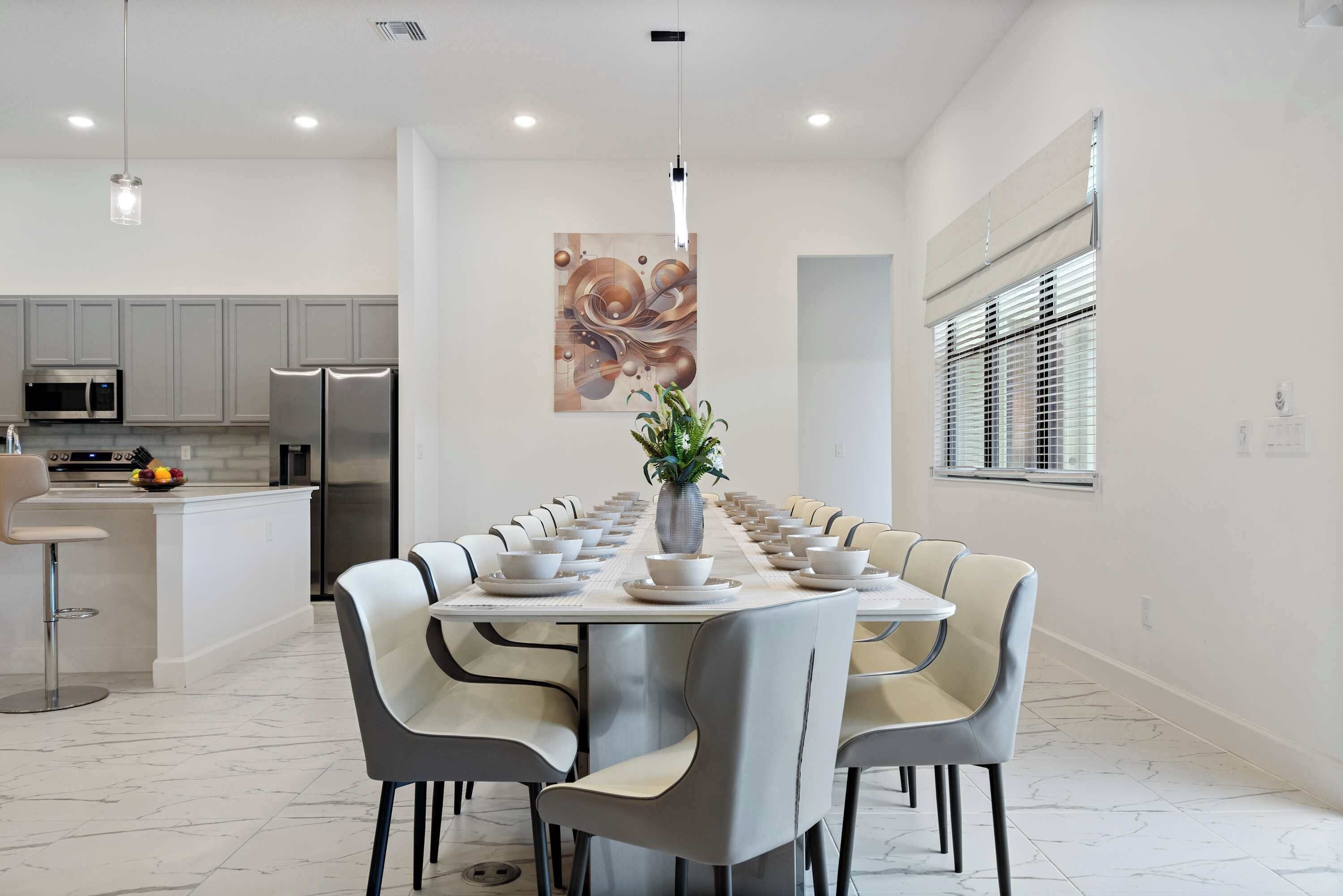 A modern dining area with a long table set for a meal, surrounded by chairs.