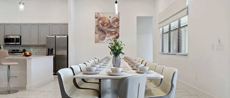 A modern dining area with a long table set for a meal, surrounded by chairs.