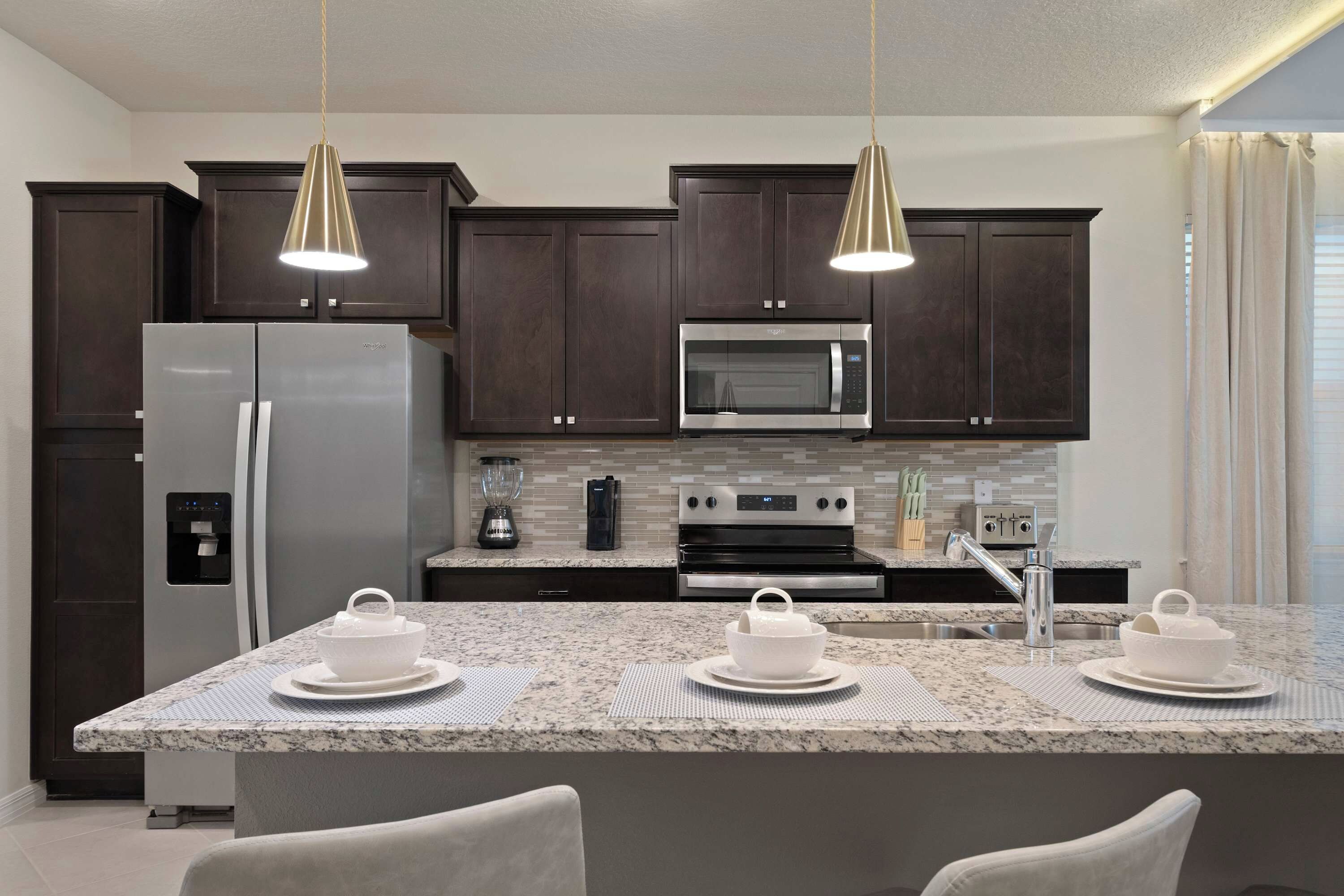 A modern kitchen with dark wood cabinets, stainless steel appliances, and a granite countertop.