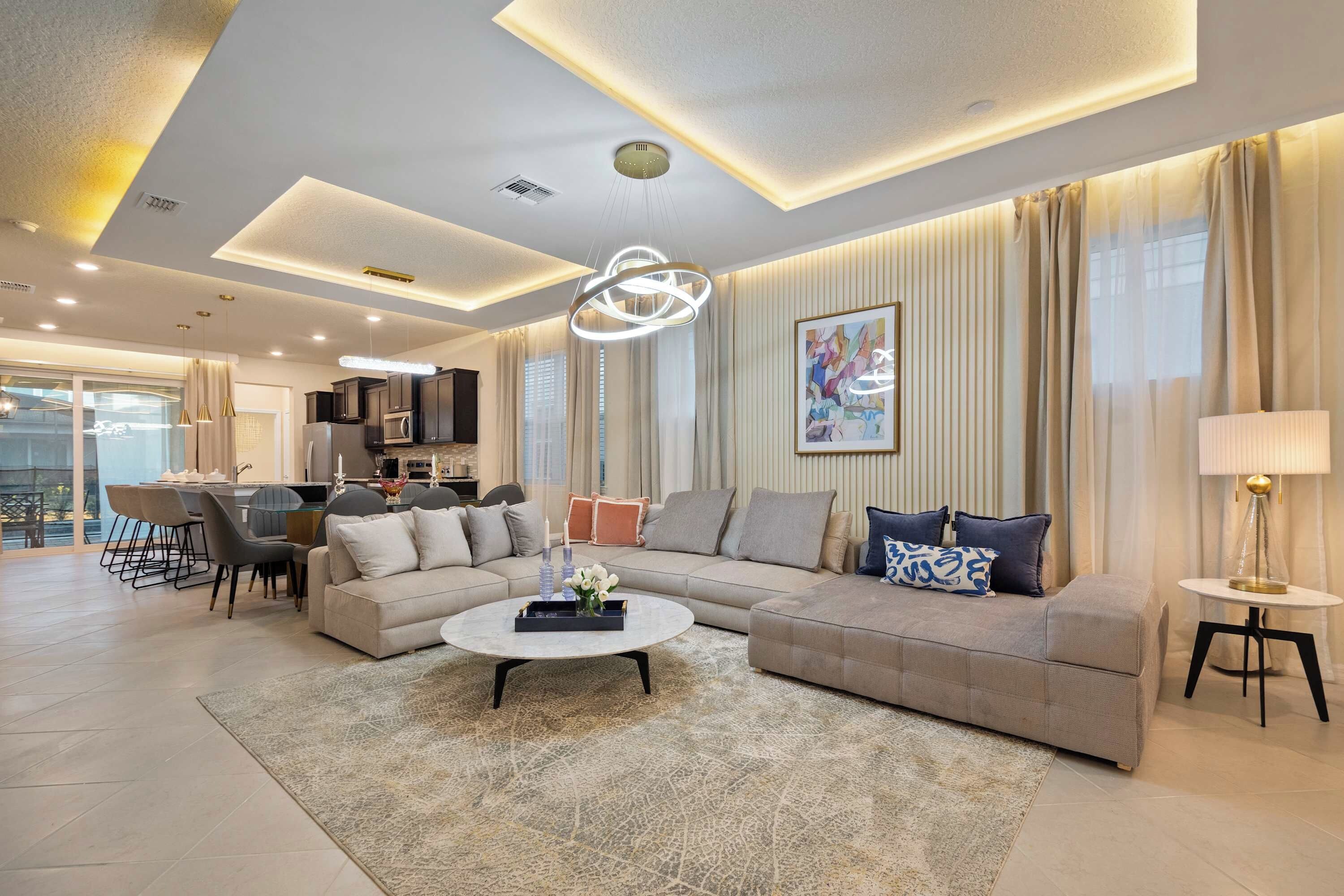 A modern living room with a sectional sofa, a coffee table, and a dining area with chairs and a table.
