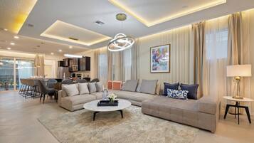 A modern living room with a sectional sofa, a coffee table, and a dining area with chairs and a table.