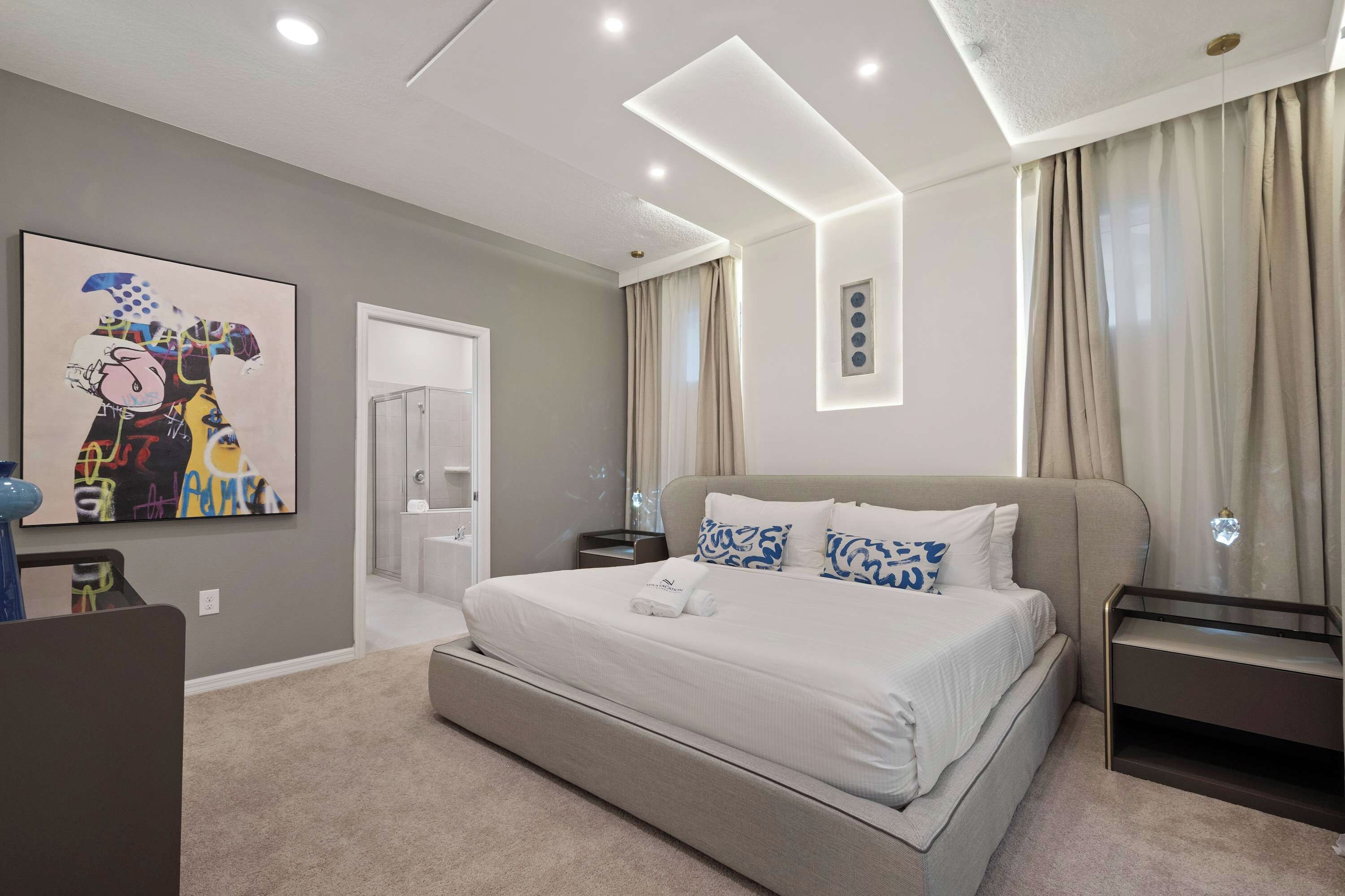 A modern hotel room with a large bed, a bedside table, a nightstand, a wall-mounted TV, and a painting on the wall.
