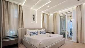A modern hotel room with a large bed, a bedside table, a glass desk, and a sliding glass door to the balcony. - Luxurious Windsor Cay Villa Private Pool, Epic Game Room & Minutes to Disney! (Clermont)