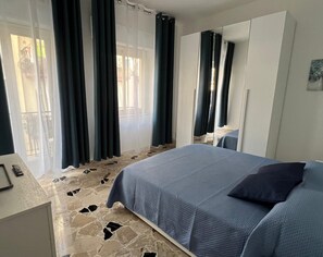 Une chambre à coucher avec un lit, un bureau et une grande fenêtre avec des rideaux.