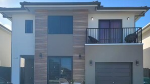 Une maison moderne à deux étages, dotée d’un garage, d’un balcon et d’une allée.