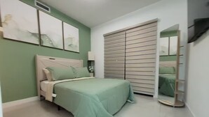 Une chambre à coucher comprenant un lit, une table de chevet, un miroir et une porte coulissante.