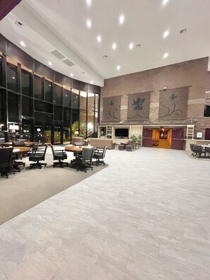 Eine geräumige Lobby mit einem großen Konferenztisch, mehreren Stühlen und einem Fernsehbildschirm.
