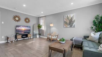A modern living room with a flat-screen TV, a wooden coffee table, a sofa, and a floor lamp.
