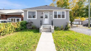 A single-story house with a front entrance, a small porch, and a front yard. - Spacious 3BDs - Close to Wineries, Brock & Falls! (Thorold)