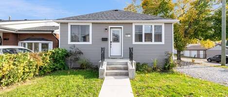 A single-story house with a front entrance, a small porch, and a front yard.