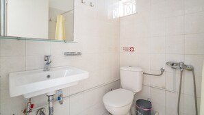 Un baño con lavamanos, inodoro y ducha blancos.