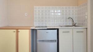 Una cocina compacta equipada con lavavajillas, un refrigerador pequeño y un lavabo con un grifo moderno.