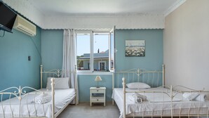 Un dormitorio con dos camas, una ventana, una lámpara y un cuadro en la pared.